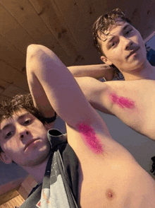 a shirtless man has pink paint on his armpits