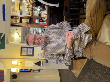 a man wearing glasses sits in front of a bar with a sign that says " exit " on it