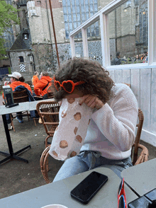 a woman wearing heart shaped sunglasses is covering her face with a bag