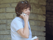 a woman is talking on a cell phone while holding a piece of paper