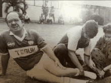 a black and white photo of a man laying on the ground with a bandage on his knee .