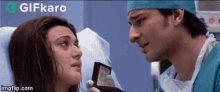 a man in a surgical cap is talking to a woman in a hospital bed while holding a wallet .