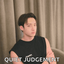 a young man with his arms crossed is wearing a black shirt that says " quiet judgement "