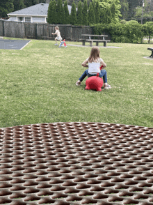 a little girl is riding a red bouncy animal