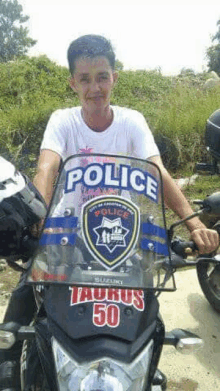 a man is sitting on a motorcycle with a police badge on the windshield .