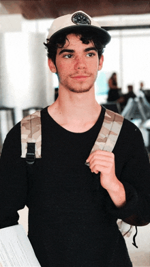 a young man wearing a hat and a backpack holds a piece of paper