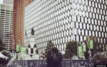 a man and woman kissing in front of a building with a green banner that says ' jl wedding ' on it