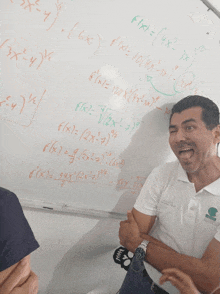 a man is laughing in front of a white board with math problems on it