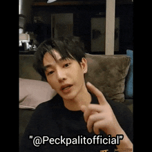 a young man is sitting on a couch and pointing at something with the words " @peckpalitoofficial " above him