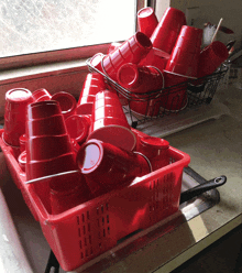 a basket of red cups sits on a counter next to a window