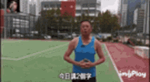 a man in a blue tank top is standing on a soccer field with his hands on his hips .