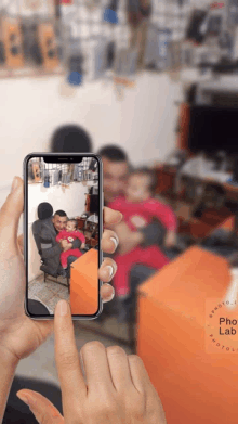 a person is taking a picture of a man holding a baby on a cell phone