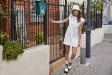 a woman in a white dress and white hat stands in front of a mailbox