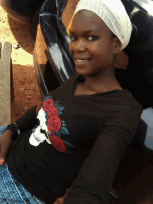 a woman wearing a black shirt with a skull and roses on it smiles for the camera