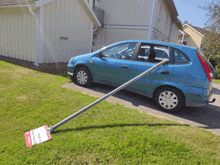 a blue car is parked on the side of the road with a sign on the grass that says " for sale "