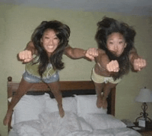 two women are jumping on a bed together .