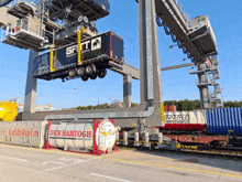 a container with den hartogh written on it is being lifted by a crane