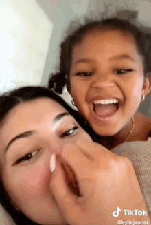 a woman is holding a little girl in her arms and the little girl is laughing .