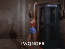 a woman in a wonder woman costume is standing in front of a telephone booth and saying i wonder .