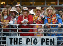 a group of people standing behind a fence with a banner that says the pig pen