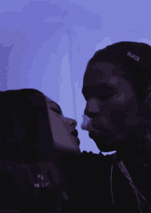 a man wearing a black hat with blvck on it kisses a woman