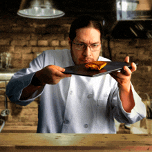 a man in a chef 's uniform is holding a plate of food