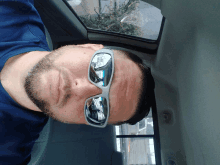 a man wearing sunglasses with a reflection of a car