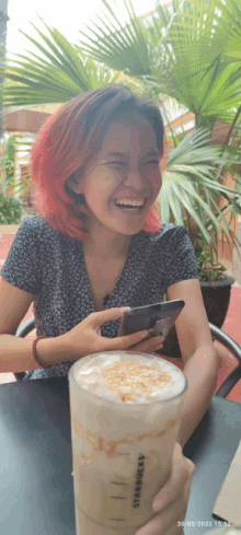 a woman holding a starbucks drink and a cell phone