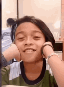 a young boy is making a funny face while sitting at a table in front of a mcdonald 's sign .