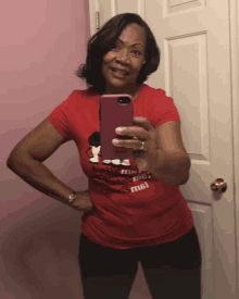 a woman in a red shirt takes a selfie in front of a mirror