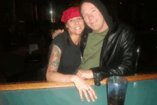 a man and a woman are posing for a picture while sitting at a bar