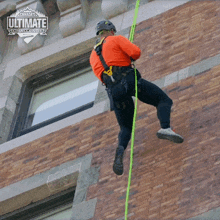 a man is hanging from a rope in front of a building that says canada 's ultimate challenge on it