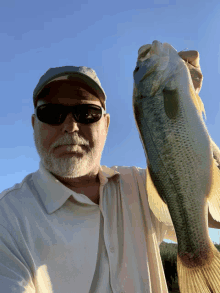 a man wearing sunglasses and a hat is holding a fish