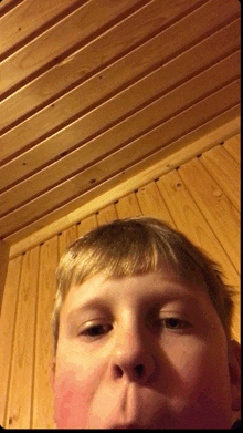 a close up of a young boy 's face with a wooden ceiling in the background