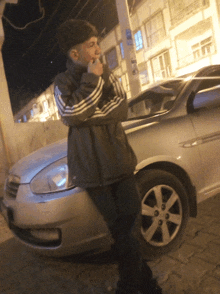 a man standing next to a silver car with a sticker on the pole that says ' a '