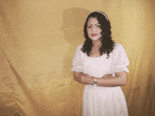 a woman in a white dress is standing in front of a yellow curtain