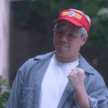 a man wearing a red hat with a clock on it is making a fist