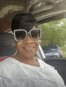 a woman wearing sunglasses is smiling in a car