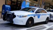 a white and blue police car is parked in front of a mailbox