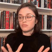 a woman wearing glasses stands in front of a shelf full of books one of which is titled " quando livro dos vampiros