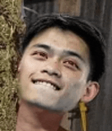 a close up of a man 's face smiling while standing next to a hay bale .