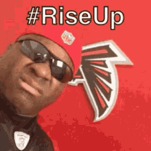 a man wearing sunglasses and a red hat is standing in front of an nfl logo .