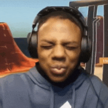 a man wearing headphones and a hoodie is making a funny face .