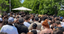 a large crowd of people are gathered under an umbrella .