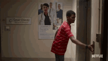 a man in a red and white striped shirt is pushing a button in an elevator at cesar chavez memorial hospital