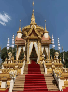 a gold and white temple with a red carpet leading up to it