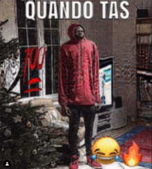 a man in a red hoodie stands in front of a window with the words quando tas