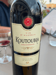 a bottle of koutoubia wine sits on a table next to a glass