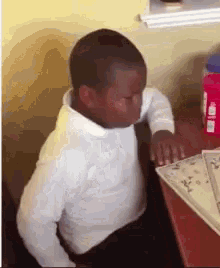 a young boy is sitting at a table with his eyes closed and a bottle of water in the background .