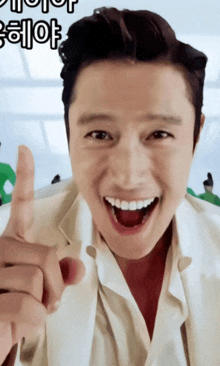 a man in a white suit giving a thumbs up with korean writing behind him